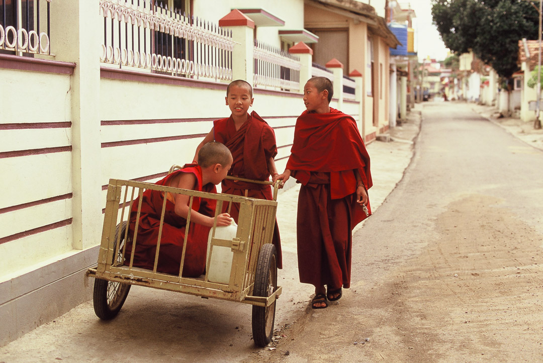 De jeunes moines boudhistes s'amusent avec une charette dans les rues de Bylakuppe